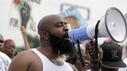 Michael Brown Sr speaks through a megaphone as he takes part in a parade in honour of his son in Ferguson