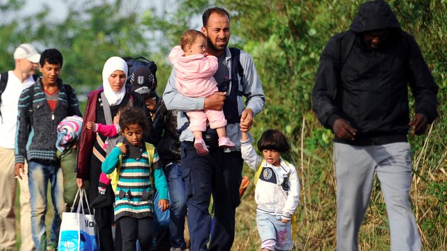 Migrant families walk between rails near the border village Roszke at the Hungarian Serbian border