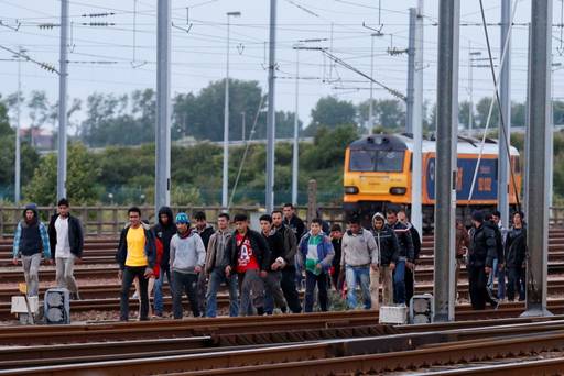 Migrants make their way along train tracks as they attempt to access the Channel Tunnel in Frethun near Calais