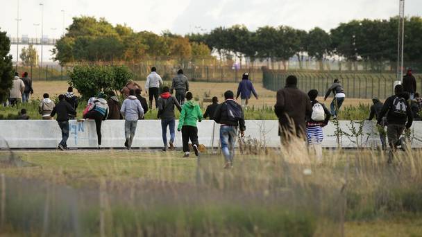 Migrants run towards the perimeter fence of the Eurotunnel site at Coquelles in Calais France