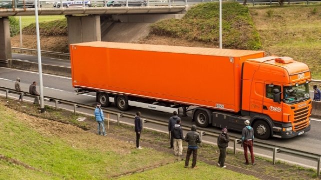 Migrants stand along the A16 highway as they try to access the Channel Tunnel