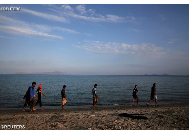 Migrants walk on a beach on the Greek island of Kos- REUTERS