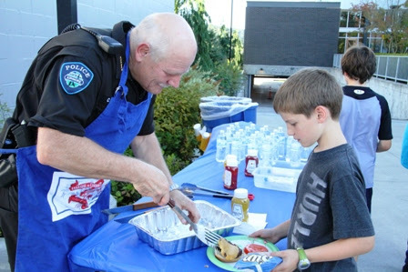 Kenmore Police Chief Cliff Sether serves up a burger to this young citizen during the 2014 National Night Out Against Crime.- Contributed