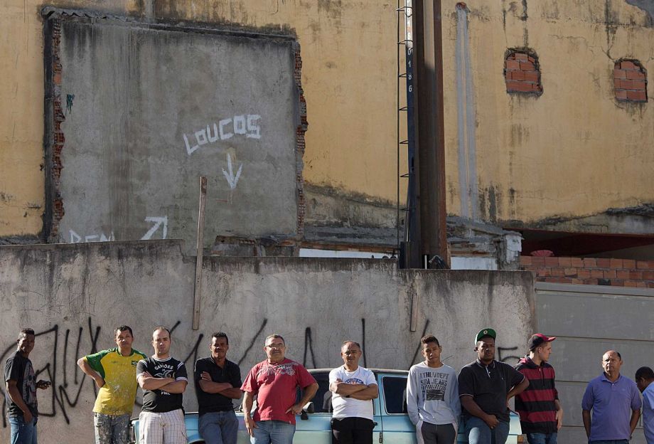 Residents stand across the street from a bar where at least 10 people were shot the night before in the Sao Paulo suburb Osasco Brazil Friday Aug. 14 2015. Police in Brazil's biggest city are investigating the shooting deaths of at least 17 people