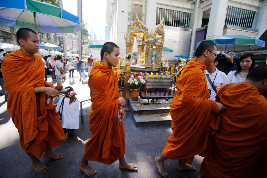 Buddhist monks walk at the Erawan Shrine the site of the explosion at Rajprasong intersection in Bangkok Thailand