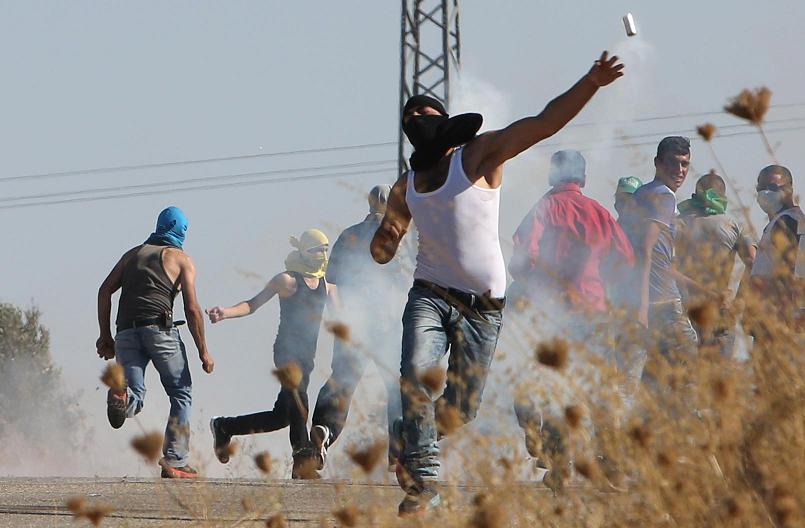 A Palestinian throws a tear gas canister back during clashes with Israeli security forces following the funeral if Saad Dawabsha the father of a Palestinian toddler killed last week when their home was firebombed by Jewish extremists. – AFP pic August