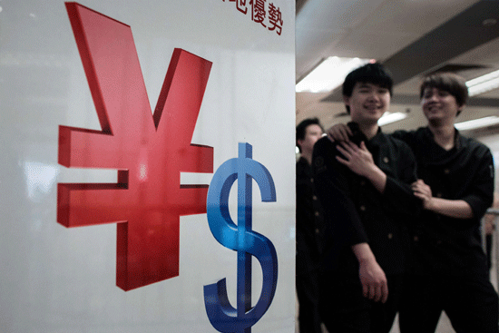 Pedestrians walk past a yuan and a US dollar currency sign in Hong Kong yesterday