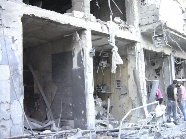 People look at damaged buildings at Al Zabadani