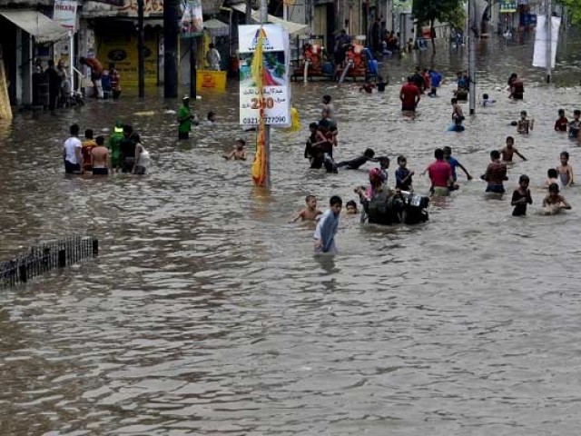 People walk through rain water following in Lahore