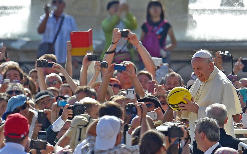 Pope Francis holds a ball that was given to him upon his arrival at his weekly audience on August 26