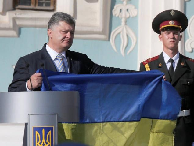 Ukraine's President Petro Poroshenko left shows the Ukrainian National flag in front of St. Sophia Cathedral on Ukraine's State Flag Day in Kiev Ukraine Sunday Aug. 23 2015 as he attends the State Flag Day