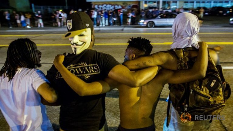 Protesters lock arms as they chant towards police officers during another night of demonstrating in Ferguson Missouri USA