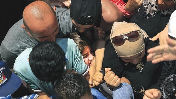 A Syrian refugee girl being squashed as others clash in the national stadium of Kos yesterday