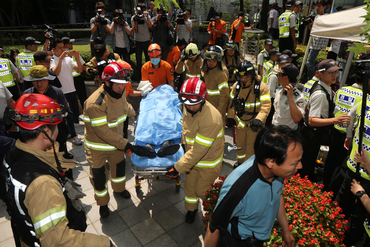 Rescue workers carry an 81-year-old man who set himself on fire during a rally