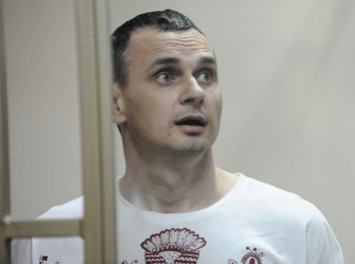 Oleg Sentsov reacts as the verdict is delivered as he stands behind bars at a court in Rostov-on-Don Russia Tuesday Aug. 25 2015. A court in the southern city of Rostov-on Don convicted Sentsov a prominent Ukrainian filmmaker of conspiring to commit