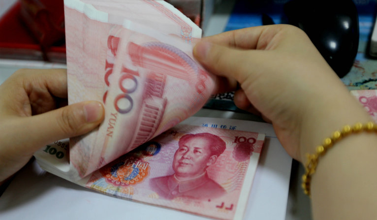 A teller counts yuan banknotes