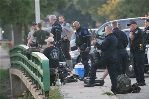 Police gather to contain a reported lion in Milwaukee on Monday. Officers armed with rifles and Department of Natural Resources staff carrying tranquilizer guns searched a ravine and surrounding neighborhood for an elusive lion-like animal after police