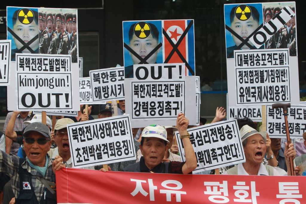 South Korean activists shout slogans and and hold placrds reading Kim jongum Out and depicting defaced portraits of North Korea's leader Kim Jong Un and flag in Seoul South Korea