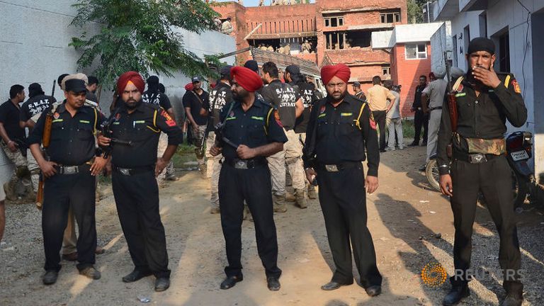 Security personnel stand at the site of a gunfight in Dinanagar town in Gurdaspur district of Punjab