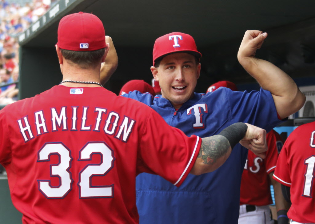 Texas Rangers starting pitcher Derek Holland compares muscles with Texas Rangers left fielder Josh Hamilton in the dugout before the Arizona Diamondbacks vs. the Texas Rangers major league baseball game at Globe Life Park in Arlington on Tuesday