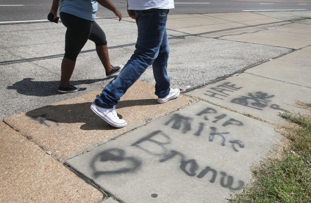 Graffiti remains on the sidewalk along West Florrisant Avenue one year after the shooting of Michael Brown one year ago. Brown was shot and killed by a Ferguson police officer