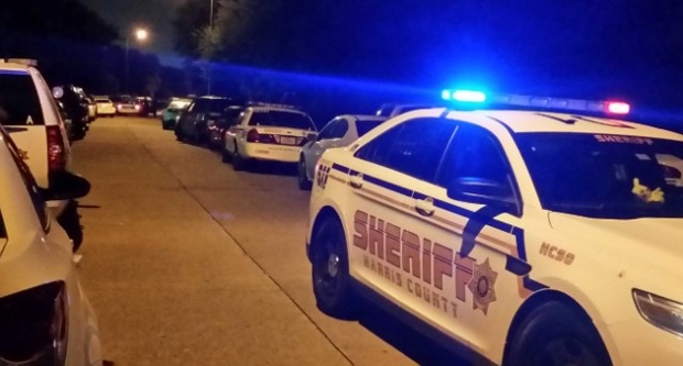 Dalila Mercado watches as officials continue to work the scene of a multiple shooting in her neighborhood Sunday Aug. 9 2015 in Houston. Eight people including five children and three adults were found dead inside a Houston-area home following the