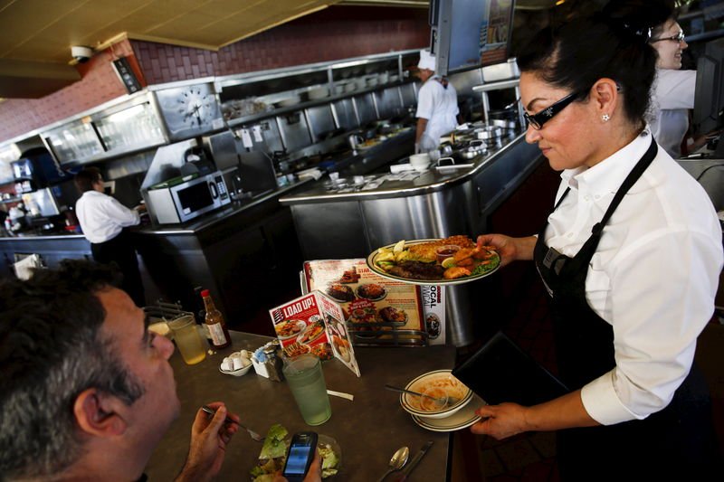 A waitress serves a steak and fried shrimp combo plate to a customer at Norms Diner on La Cienega Boulevard in Los Angeles California