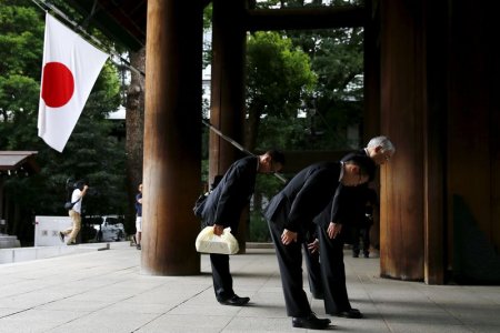 Men bow before entering Yasukuni Shrine on the anniversary of Japan's surrender in World War Two in Tokyo