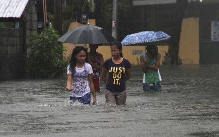 Residents wade across floodwaters caused by Typhoon Goni in Bacnotan La Union in northern Philippines