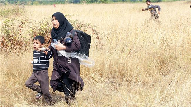 Migrants cross a field after jumping over a fence on the border between Greece and Macedonia near the town of Gevgelija