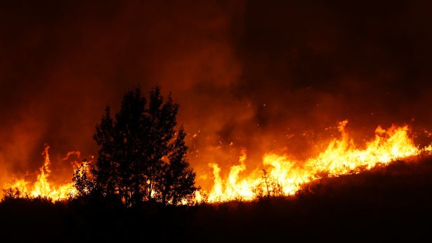 Flames rise near a tree on the ridge line above several homes on Twisp River Road just after midnight on Thursday in the Washington town