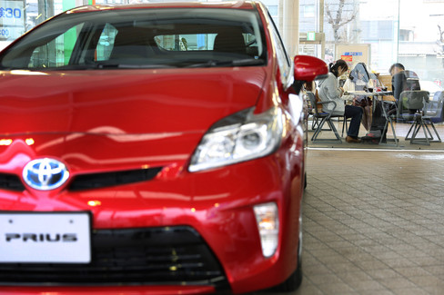 A Toyota Motor Corp Prius hybrid vehicle is displayed for sale as customers sit inside one of the company's Netz dealership in Toyota City Aichi Prefecture Japan