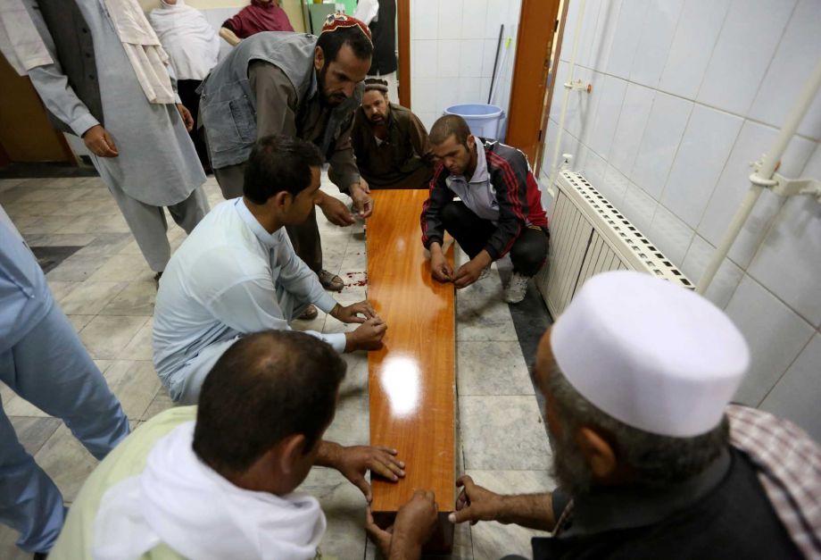 Afghans prepare to carry the dead body of a victim in a car bomb attack at a hospital in Kabul Afghanistan Friday Aug. 7 2015. A bomb hidden in a truck exploded in the center of the Afghan capital. Police chief Abdul Rahman Rahimi said the pre-dawn