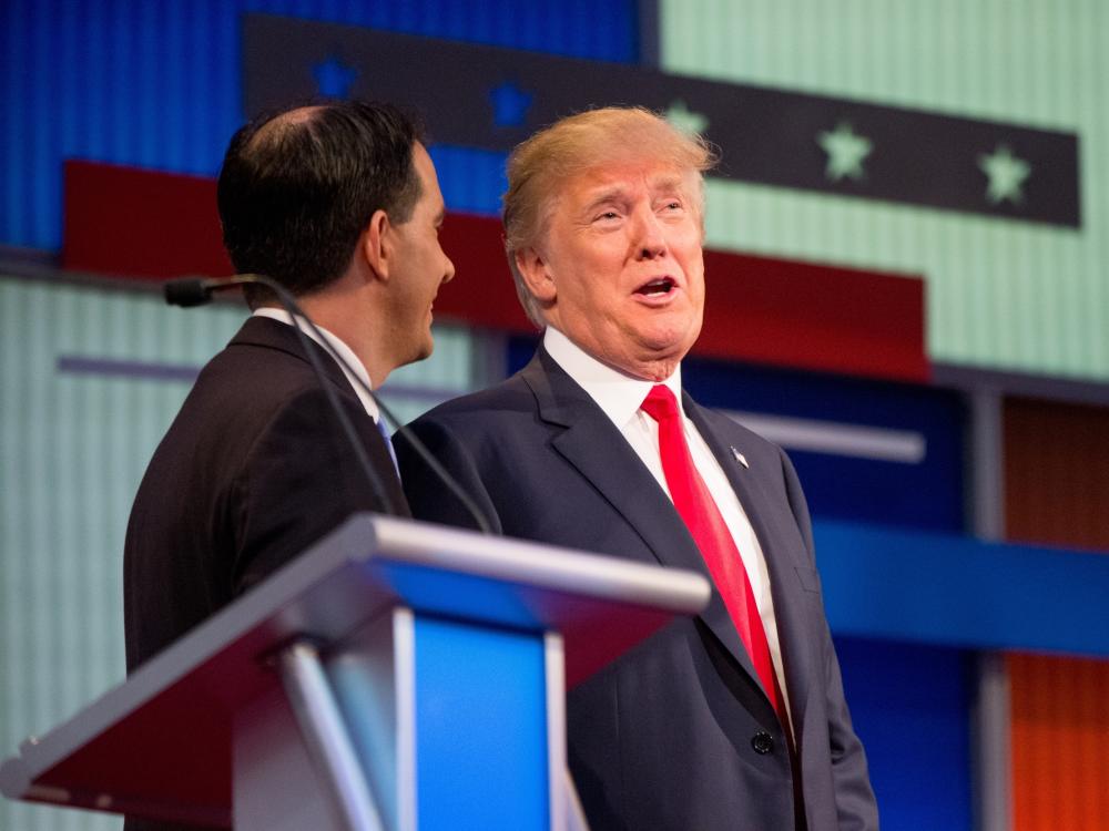 Republican presidential candidates Donald Trump and Wisconsin Gov. Scott Walker speak together during a commercial break at the first Republican presidential debate in Cleveland on Thursday. Trump's remarks about Fox News debate moderator Meg