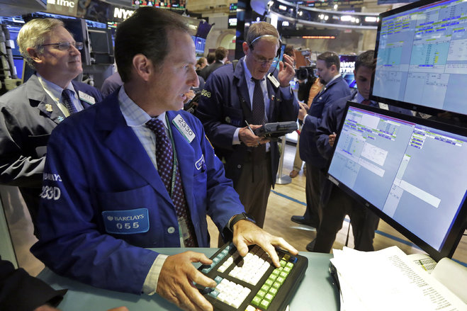 Specialist Glenn Carell foreground works with traders at his post that handles Twitter on the floor of the New York Stock Exchange Wednesday