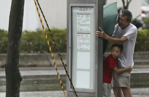 A man and a boy shelter from Typhoon Soudelor's strong winds behind a bus stop in Taipei Taiwan on Aug. 7 2015