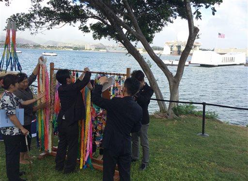 People hang paper cranes folded for peace near a memorial to the sunken battleship USS Arizona before a ceremony marking the 70th anniversary of the end of World War II Friday Aug. 15 2015 in Pearl Harbor Hawaii. Mayors and city council members from