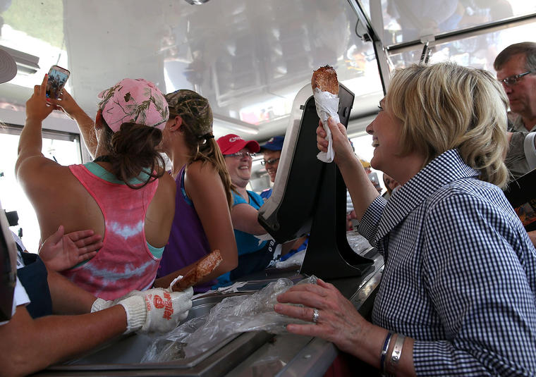 Democratic presidential hopeful Hillary Clinton holds a Pork Chop on a Stick as she takes a selfie with booth worker while touring the Iowa State Fair Aug. 15 2015 in Des Moines Ia