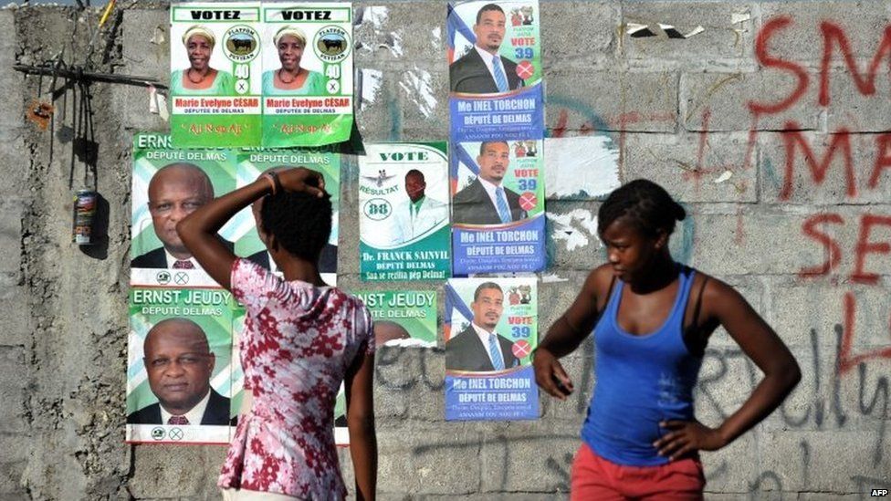 Women stand in front of election posters in Port-au-Prince Haiti