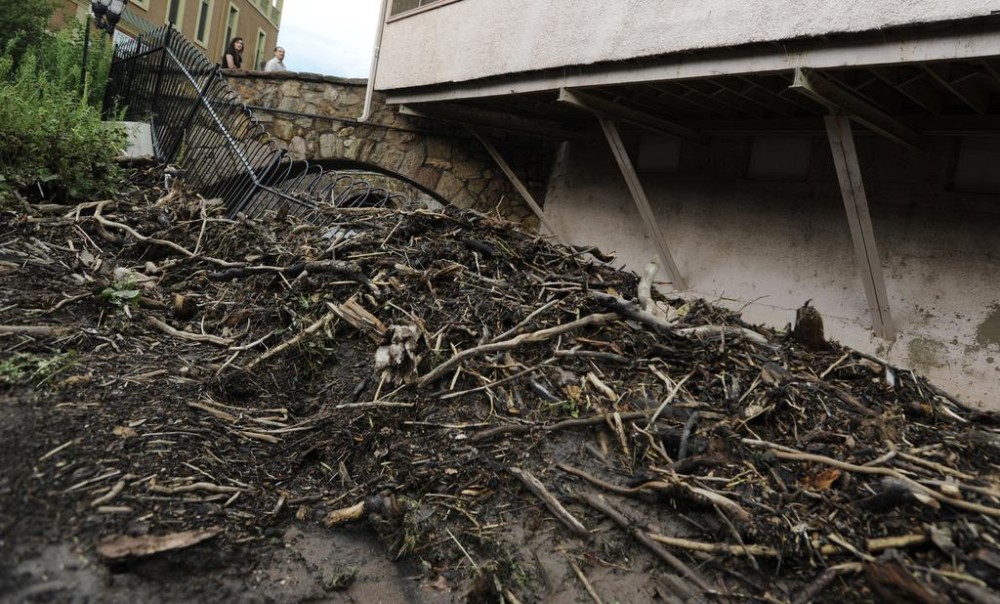 People look at debris that damaged a fence in Soda Springs Park Monday Aug. 10 2015 in Manitou Springs Colo. after heaving rain caused flash flooding in the area. MAGS OUT MANDATORY CREDIT