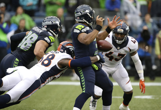 Seattle Seahawks quarterback Russell Wilson has the football stripped by outside linebacker Von Miller lower left for a fumble in the first half of a preseason NFL football game Friday Aug. 14 2015 in Seattle. Denver recovered the ball. (AP