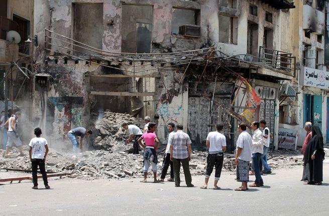 Yemeni people inspect the damage to a building in Aden used for illustrative purposes