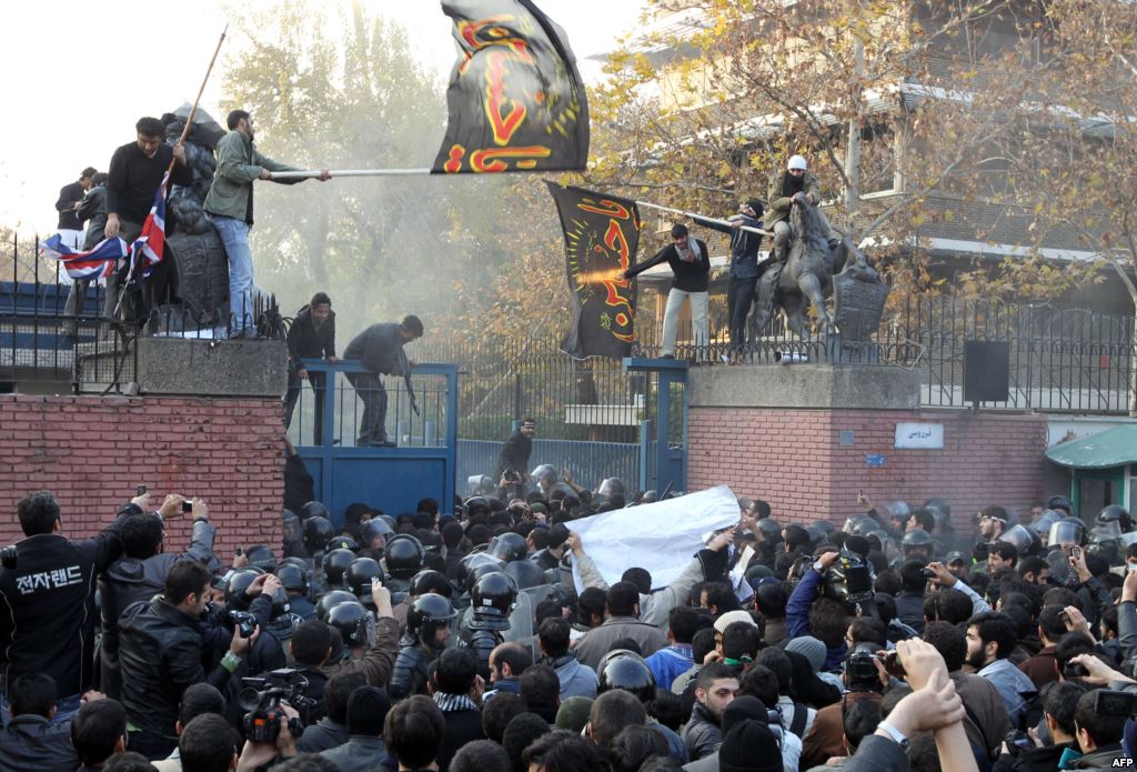 Iranian protesters gather outside the British embassy as some break into it and bring down the British flag, Tehran