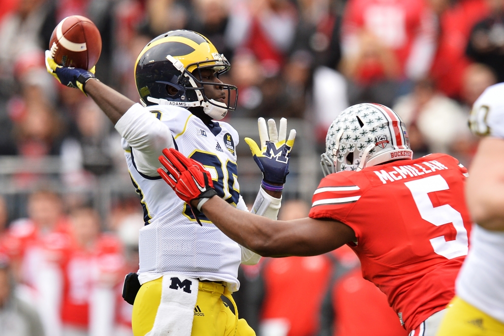 COLUMBUS OH- NOVEMBER 29 Quarterback Devin Gardner #98 of the Michigan Wolverines tosses a 12-yard touchdown pass as he is rushed by Raekwon Mc Millan #5 of the Ohio State Buckeyes in the first quarter at Ohio Stadium