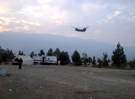 A Chinook helicopter drops off search teams on Aug. 25 2015 as a nearby forest fire glows in the distance