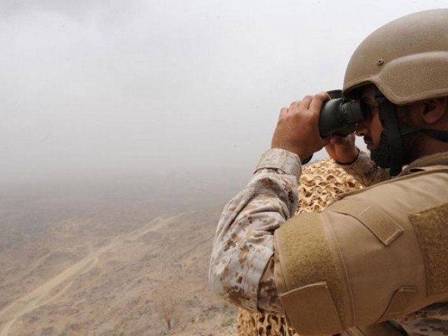 A Saudi soldier looks through binoculars from a position on the Saudi Yemeni border in southwestern Saudi Arabia