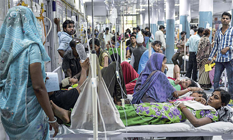 An 18 year-old patient Radha suffering from dengue shares her bed with other patients in a casualty ward of a government hospital