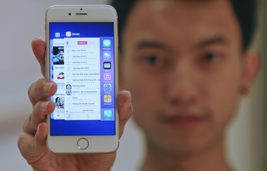 A sales assistant shows features of iOS 9 on an Apple iPhone 6 at an Apple reseller shop in Bangkok