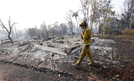 Firefighter Thomas Fitzpatrick walks past the remains of a house destroyed in a wildfire several days earlier Tuesday Sept. 15 2015 in Middletown Calif. The fire that sped through Middletown and other parts of rural Lake County less than 100 miles