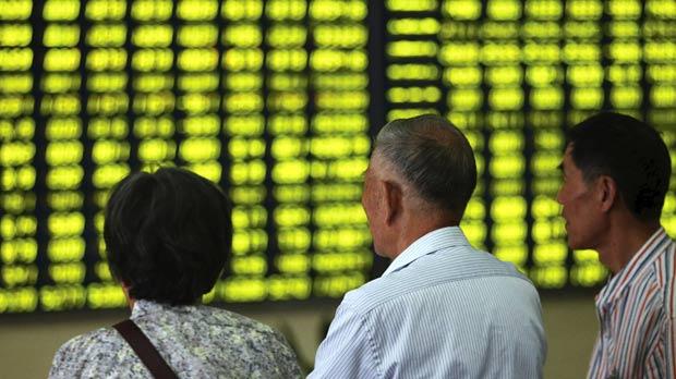 Investors looking at an electronic board showing stock information filled with green figures indicating falling prices at a brokerage house in Nantong Jiangsu province China yesterday